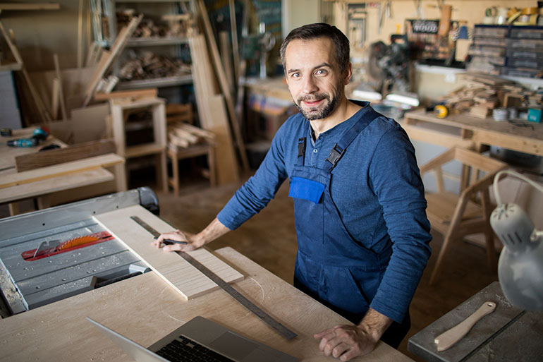 Carpenter standing next to his woodworking desk